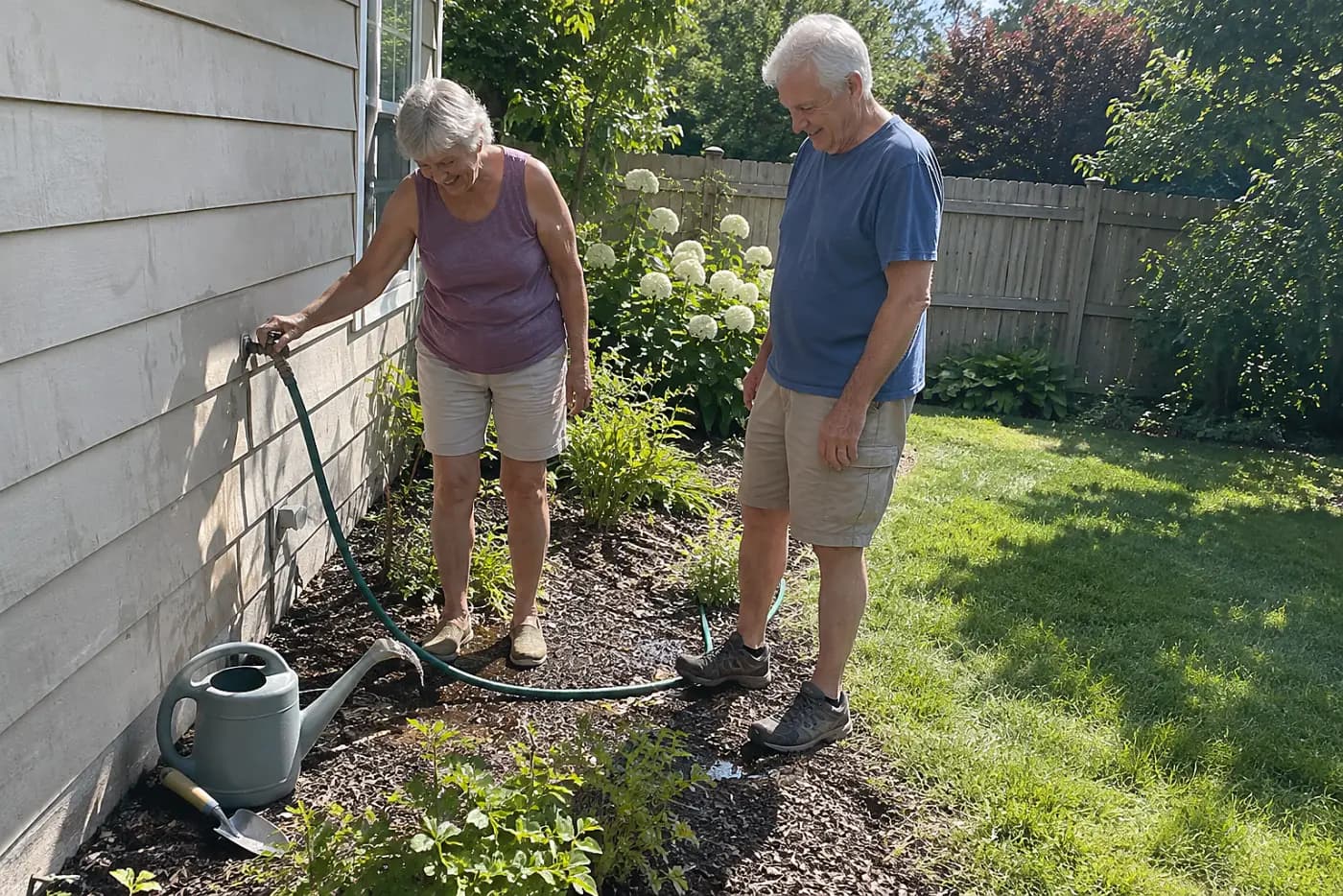 Older woman unscrewing a garden hose from an outdoor faucet.