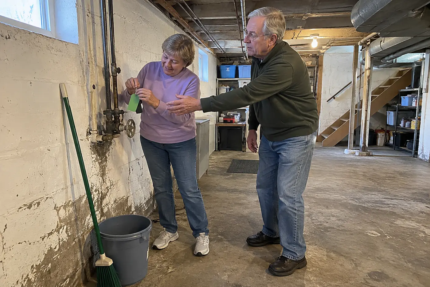 Older woman attaching a label to the main water shutoff in her basement.