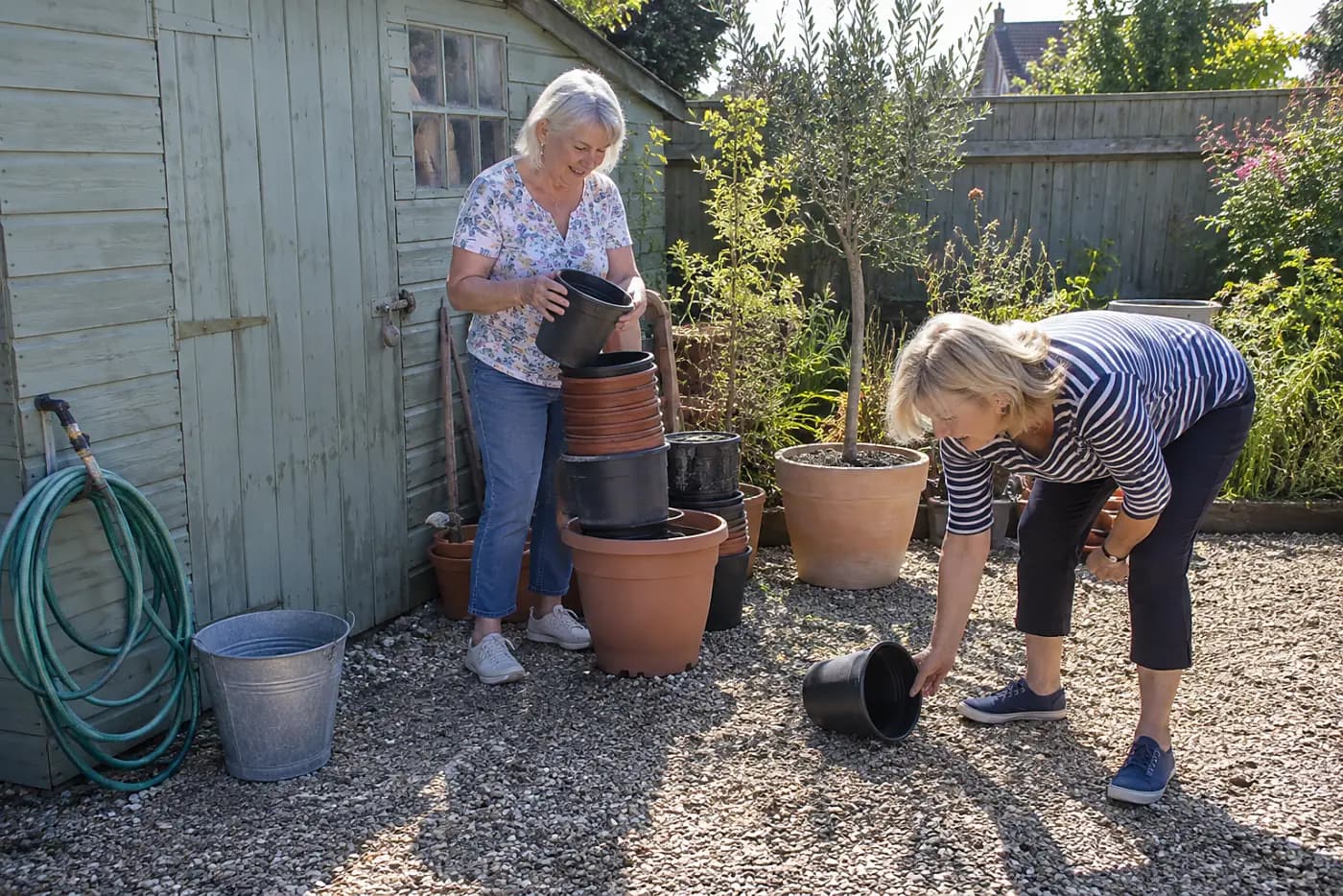 Woman sorting nursery pots beside a garden shed.