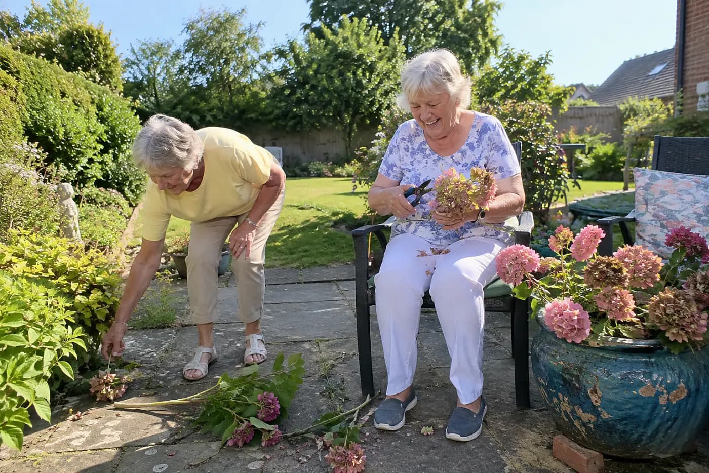 Older woman pruning flowers from a sturdy chair beside her garden.
