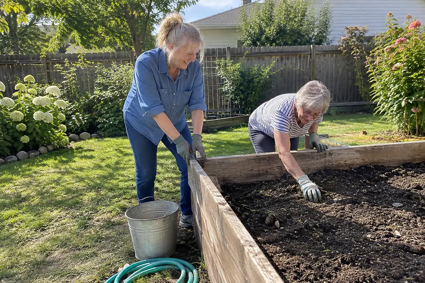Older woman pressing a loose corner of a raised bed in her garden.