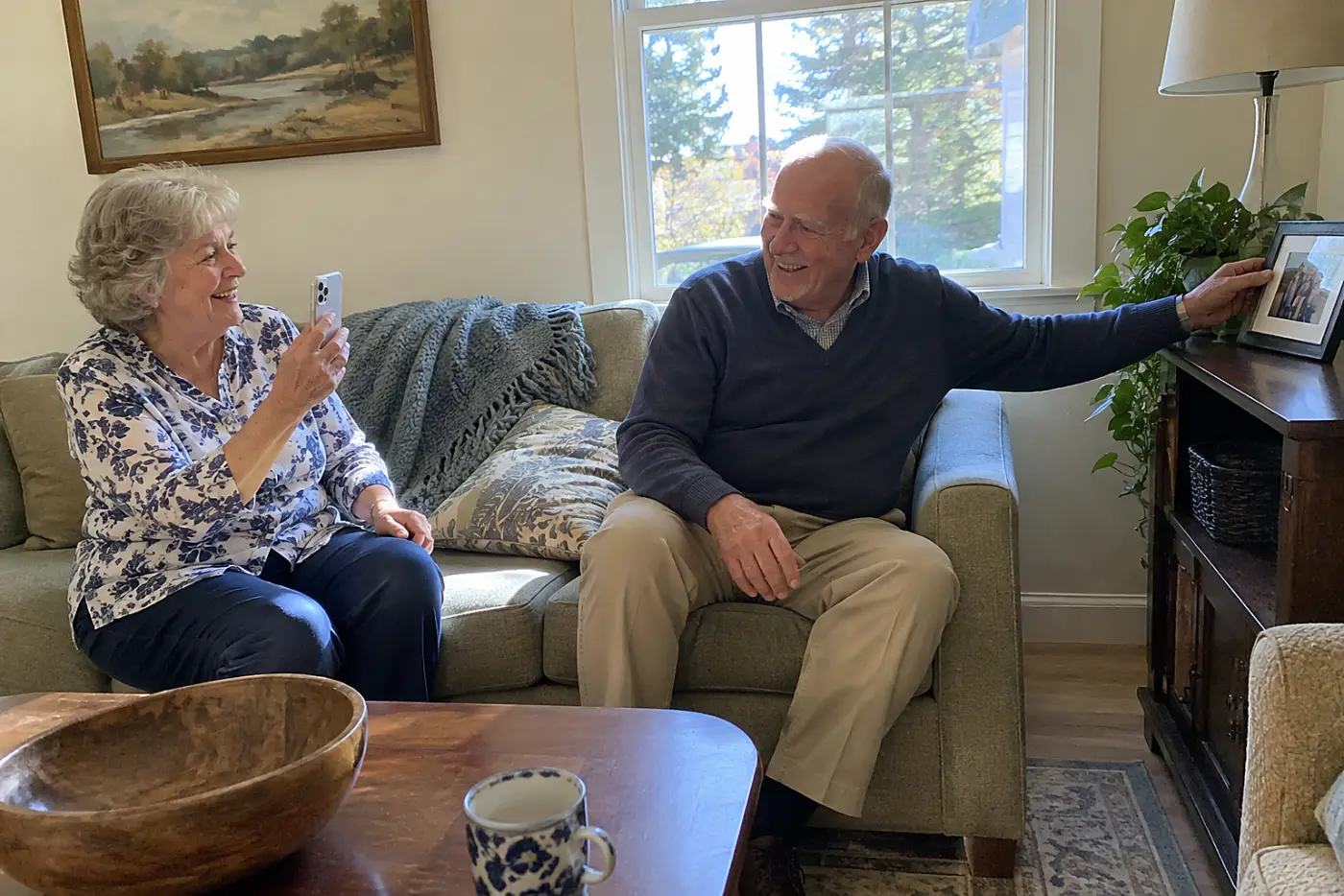 Grandmother recording a story on her phone beside a family photograph in her living room.
