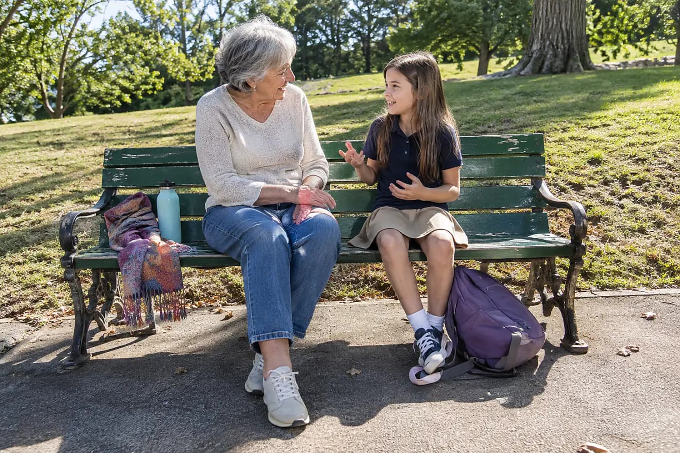 Grandmother sitting beside a child on a park bench after school.