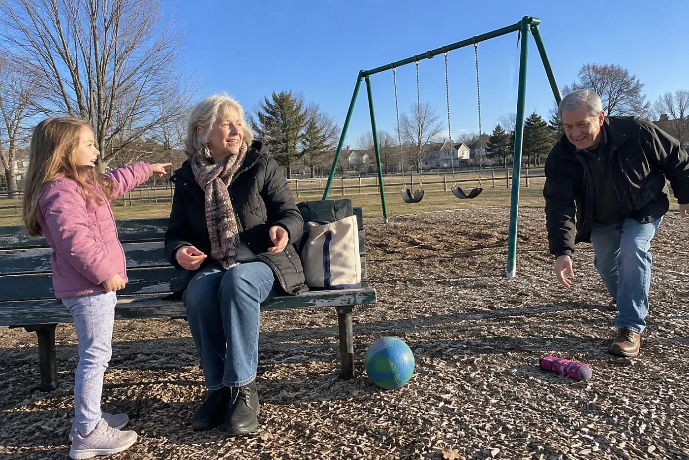Older woman listening as a child talks beside a playground bench.