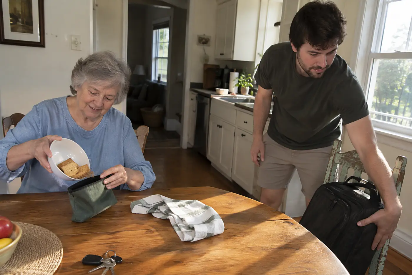 Grandmother packing crackers into a carry-on bag at her kitchen table.