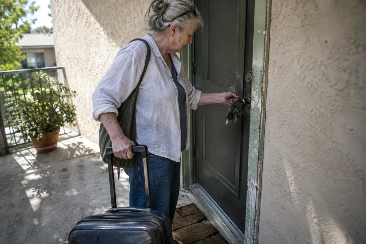 Woman unlocking a timeshare condo door with a worn suitcase in hand