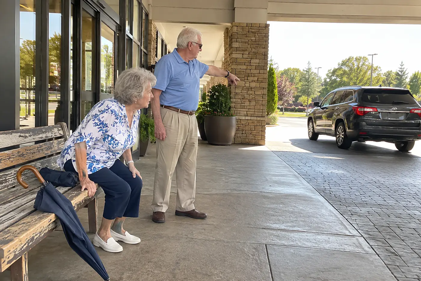 Older woman sitting near a hotel entrance while waiting for a car.
