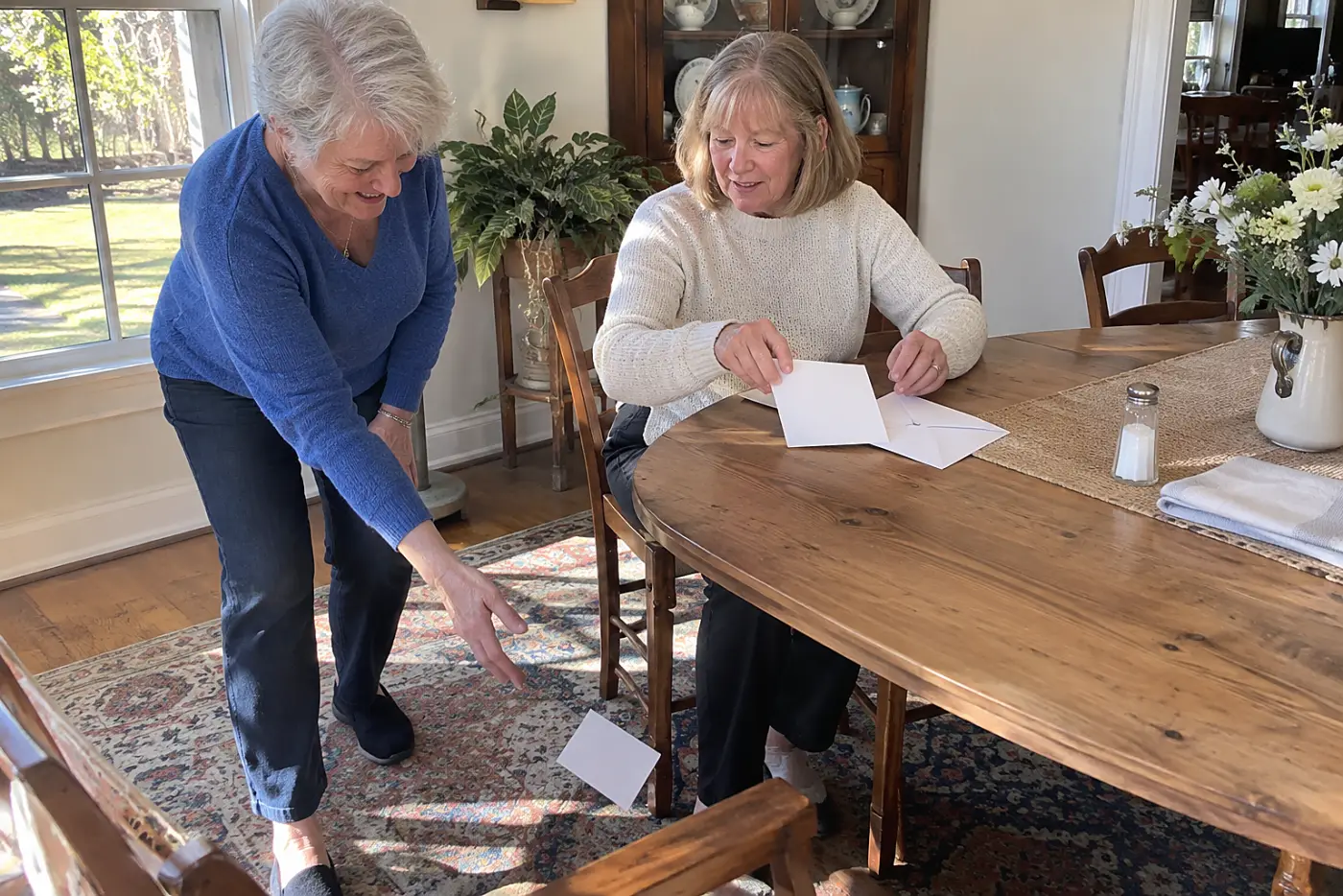 Woman comparing Medicare cards with plan notices at her dining table.