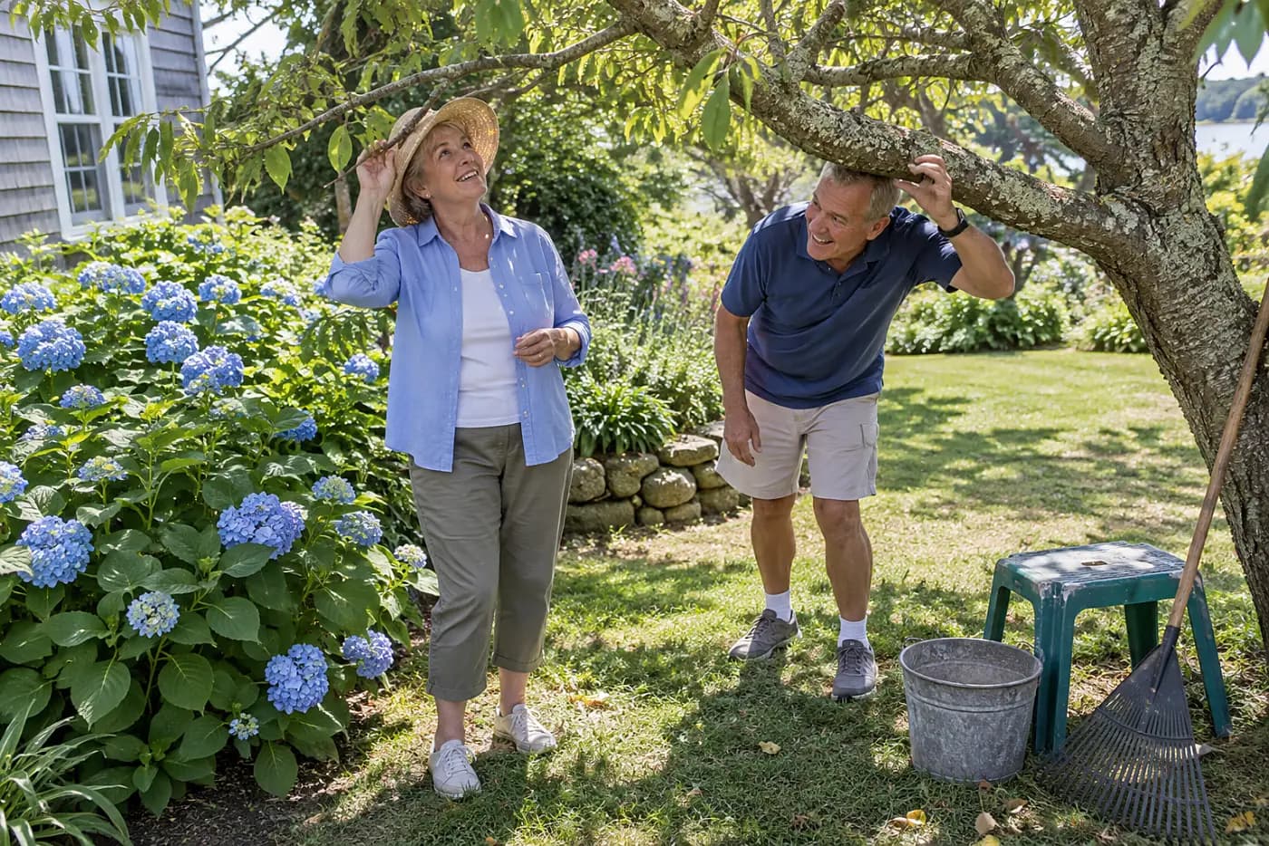 Woman looking up through tree branches above a hydrangea in her garden.
