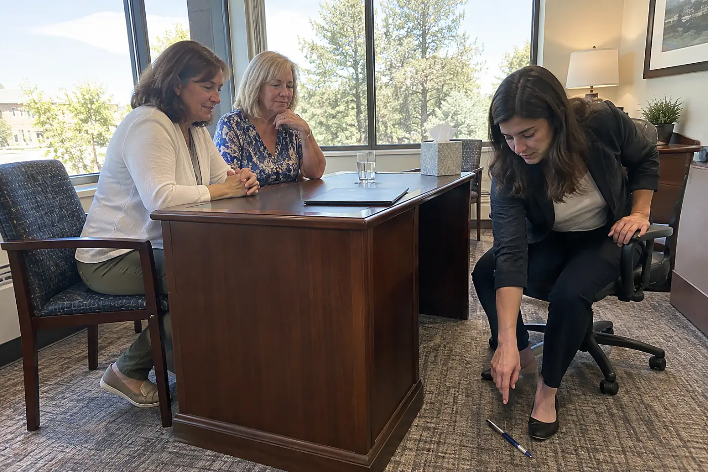 Mother and daughter reviewing a form across a bank desk.