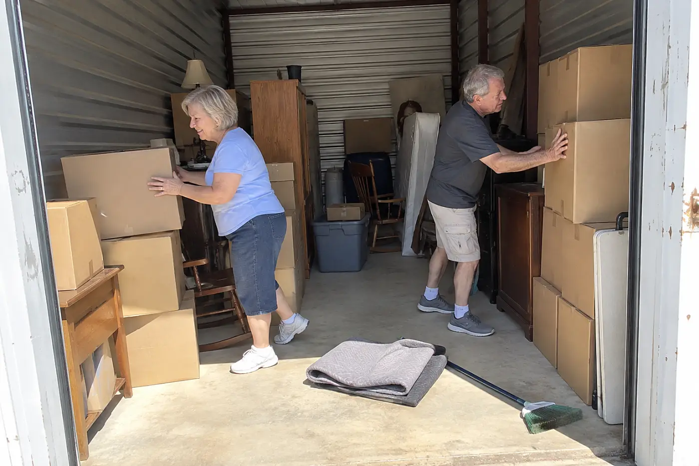 Older woman sorting sealed boxes in a storage unit.