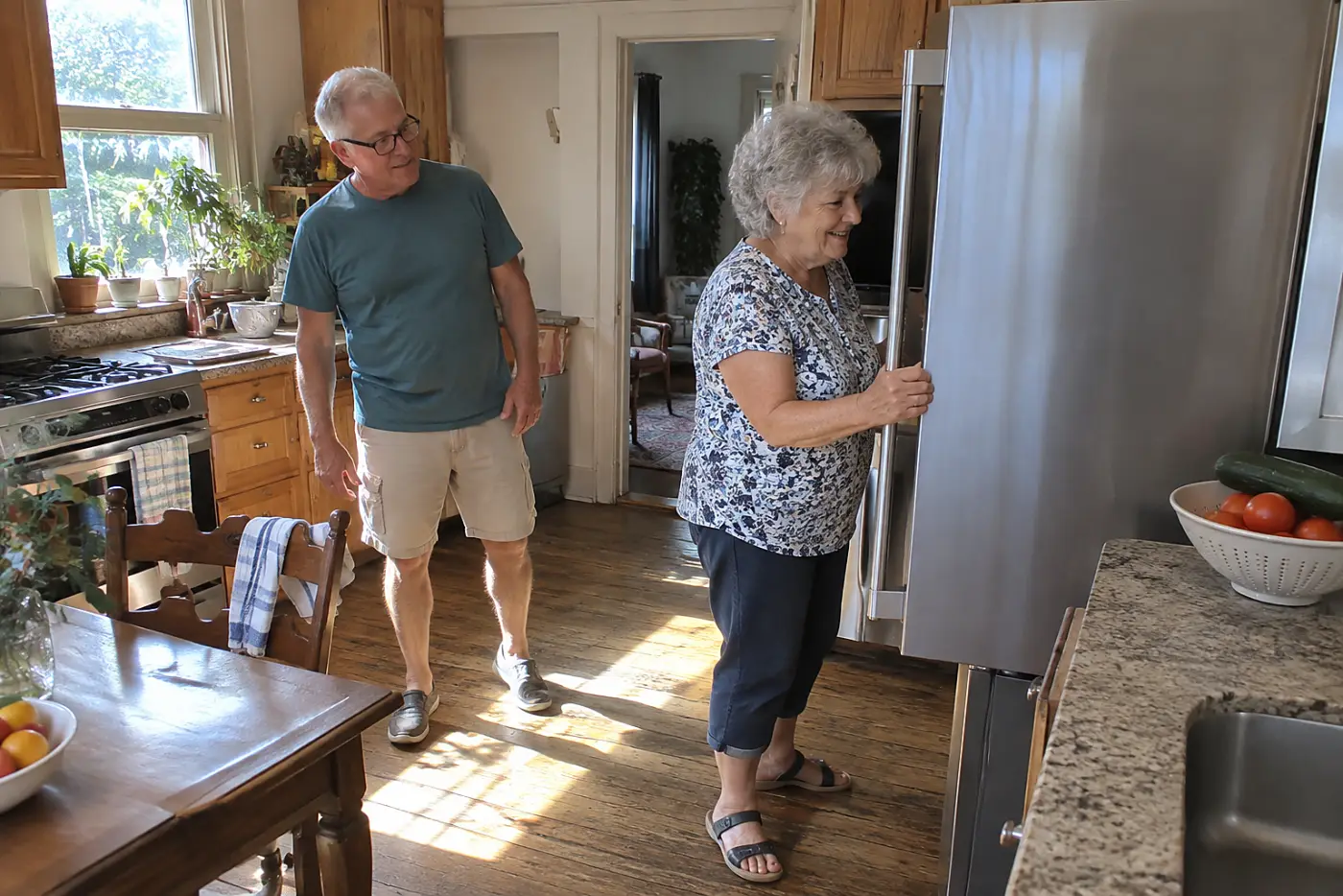 Woman opening a refrigerator door beside a kitchen wall.
