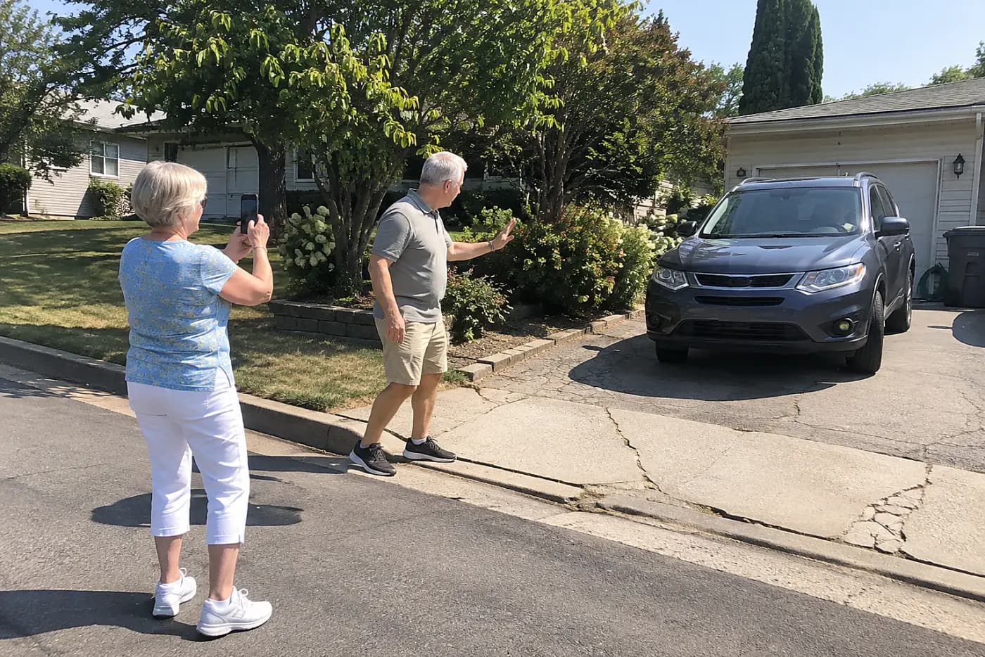 Woman photographing a narrow driveway from the street.