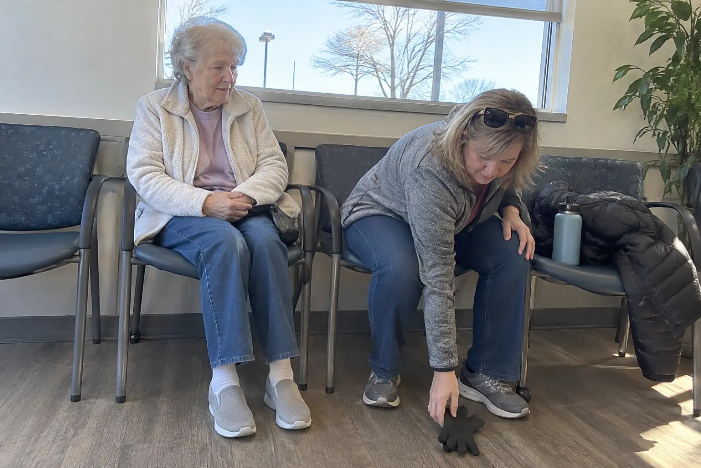 Older woman sitting with a family member in an urgent care waiting room.