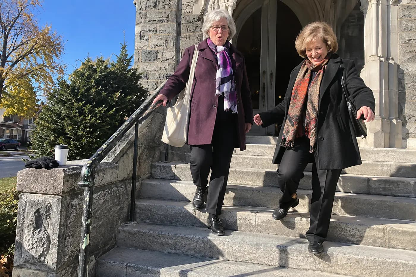 Two older women leaving a church building after choir practice.