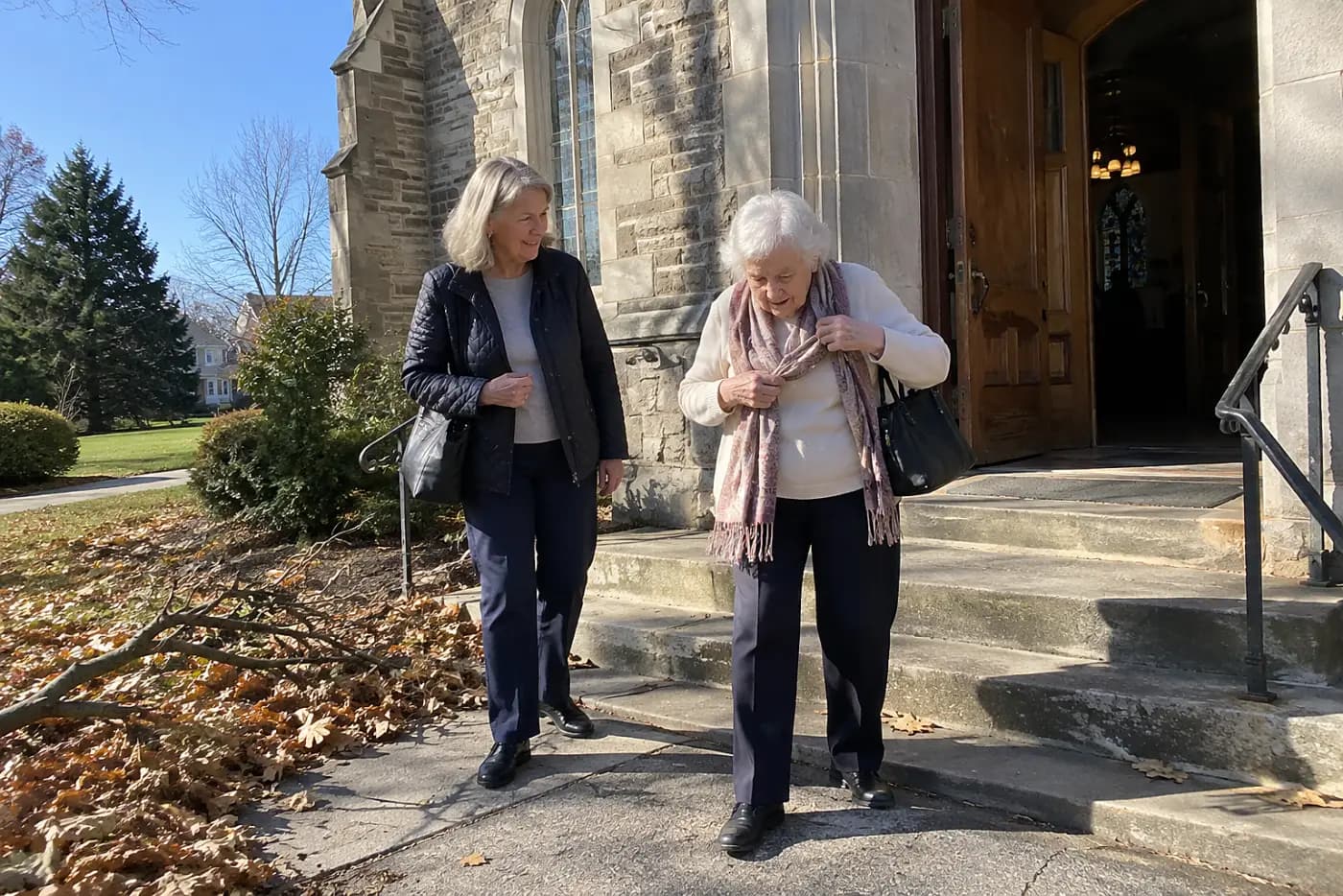 A woman waits outside a church entrance with her mother.