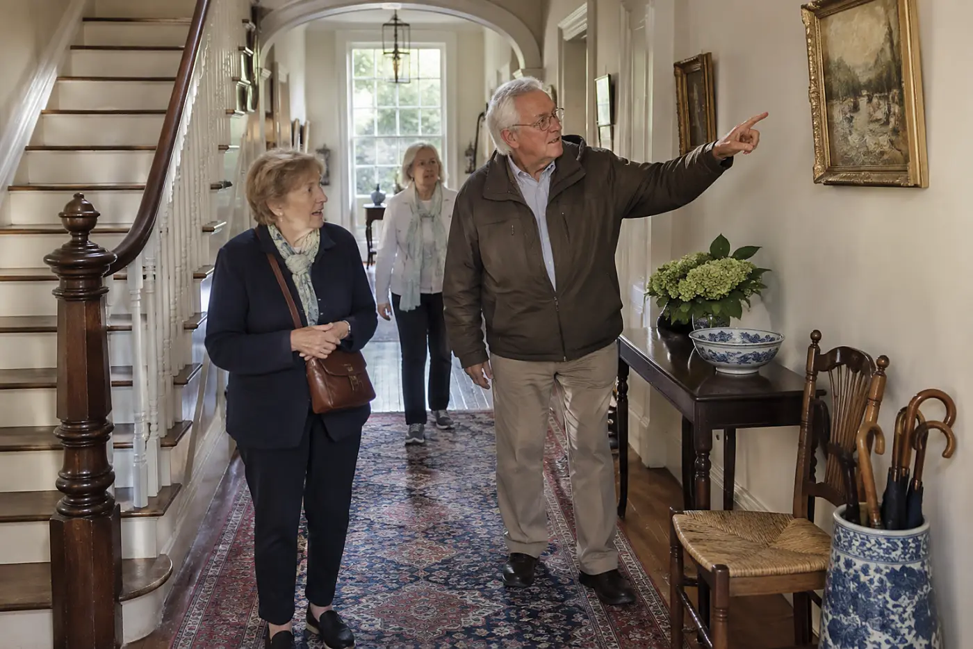 Older woman leading visitors through a historic house hallway.