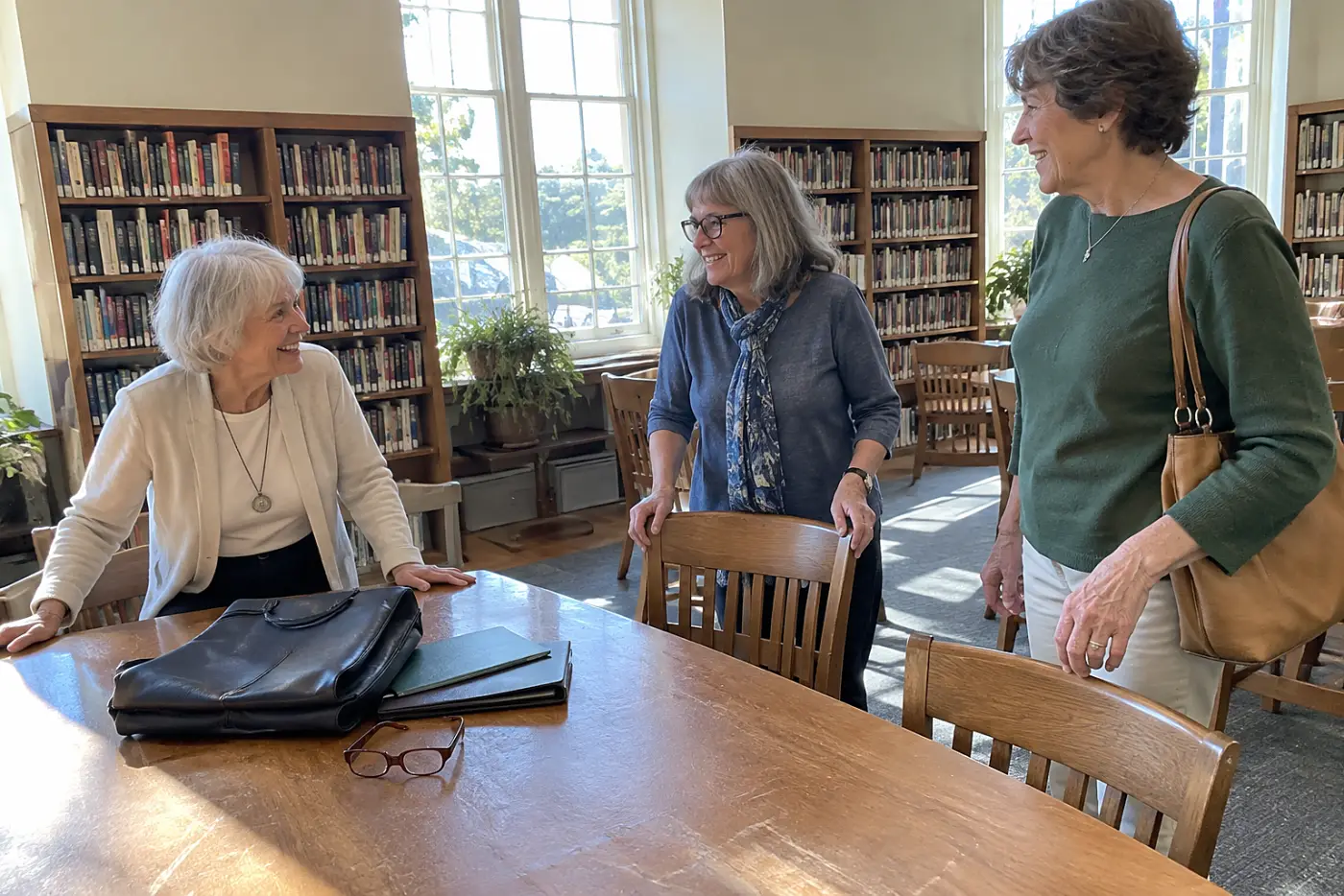 Older woman greeting friends at a library table on Thursday afternoon.