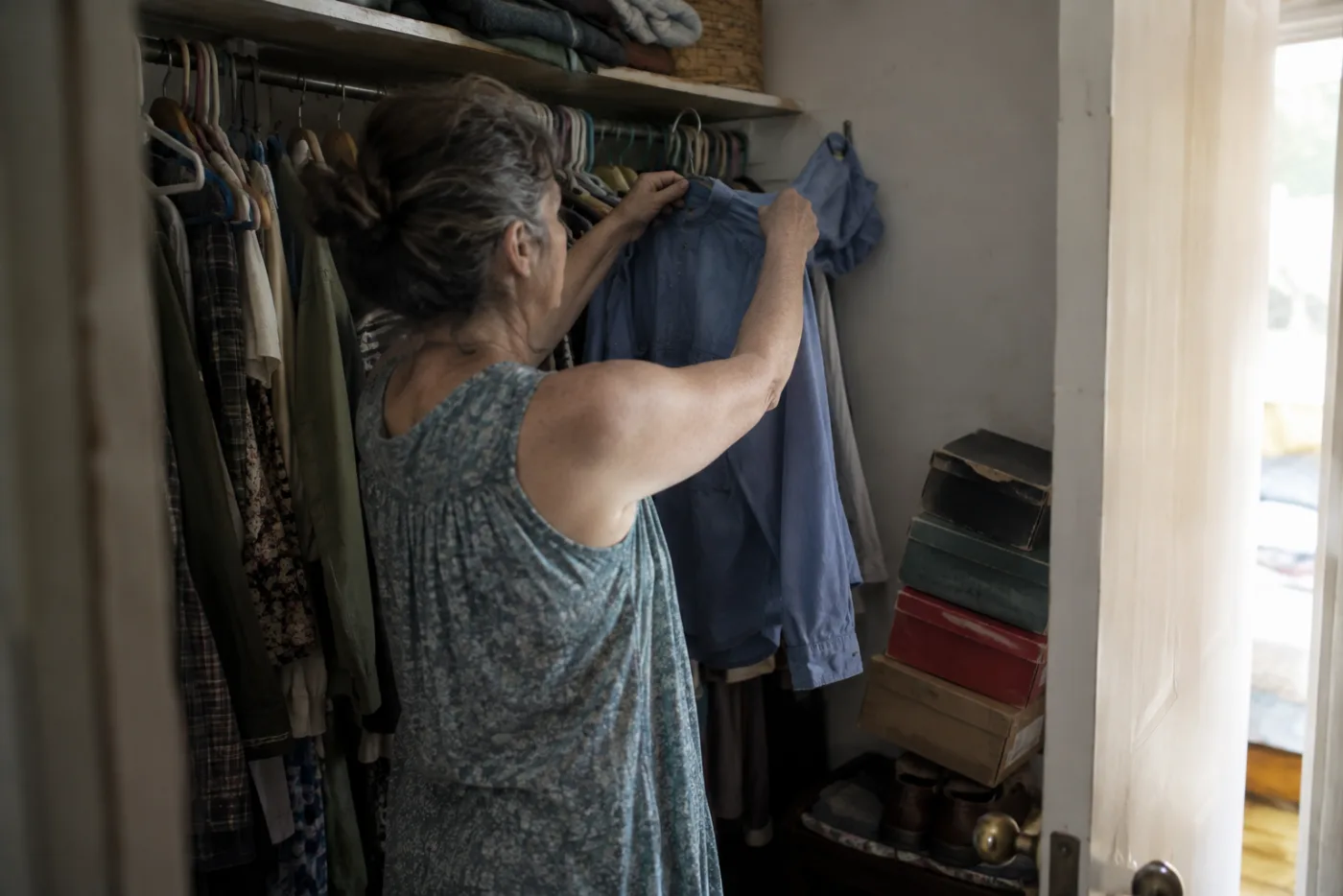 Woman hanging a shirt back onto a crowded closet rail