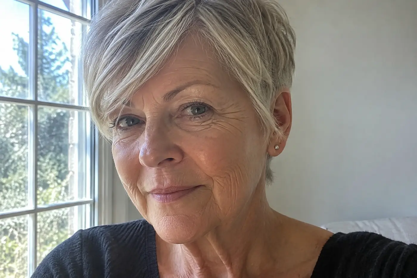 A sleek pixie with side fringe is centered on a woman in her sixties seen from the front and slightly to one side in daylight, with no writing visible.