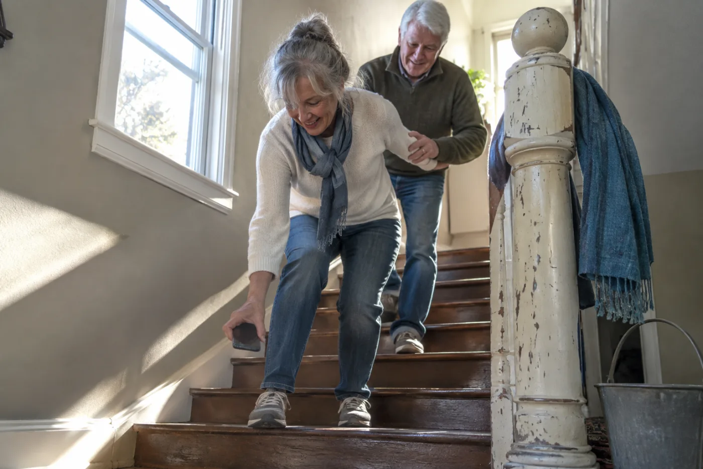 Older woman stepping onto a wooden stair while recording with her phone.