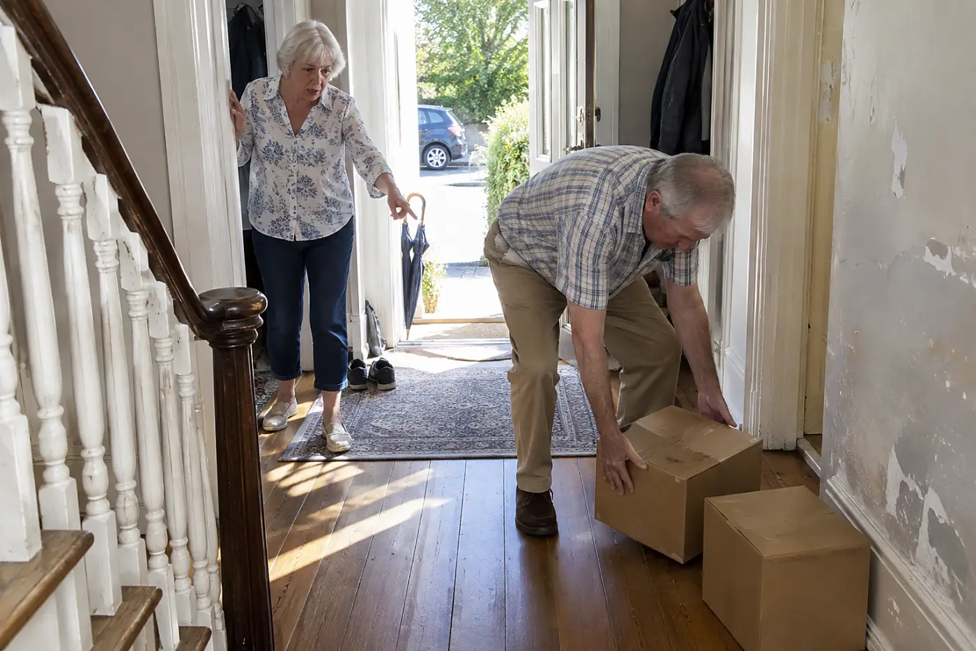 Older woman pointing out boxes to a relative in her hallway.