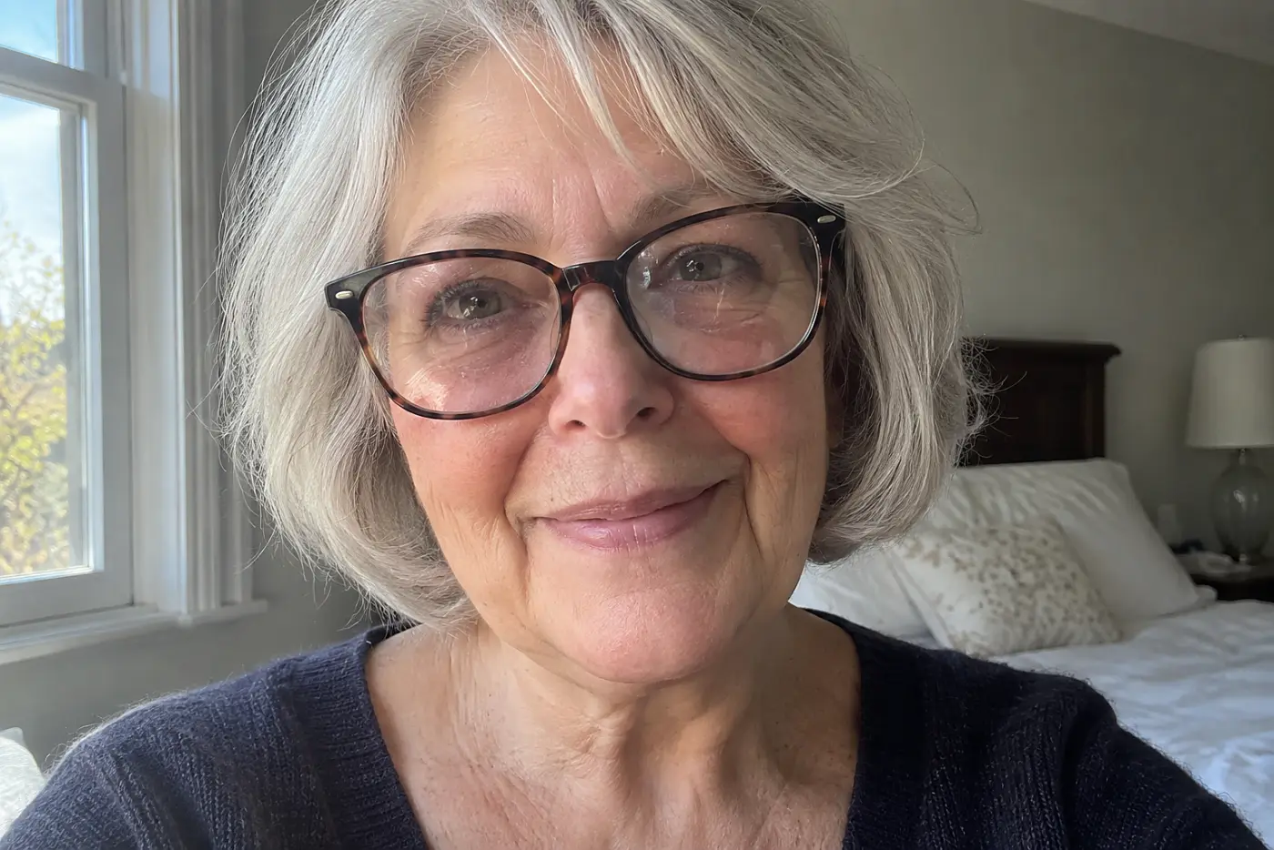 Fine scratches across both lenses sit in the middle of a close daylight view of glasses held by a woman in her sixties.