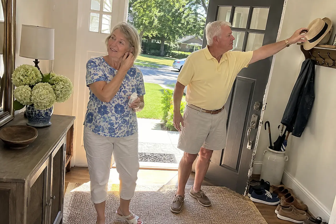Older woman applying sunscreen to her ear beside a front door.