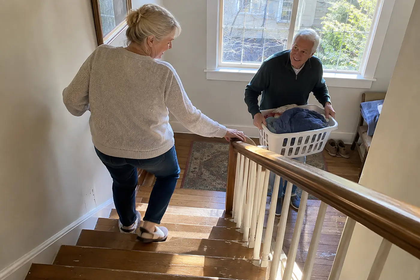 Older woman holding the handrail while descending the stairs at home.
