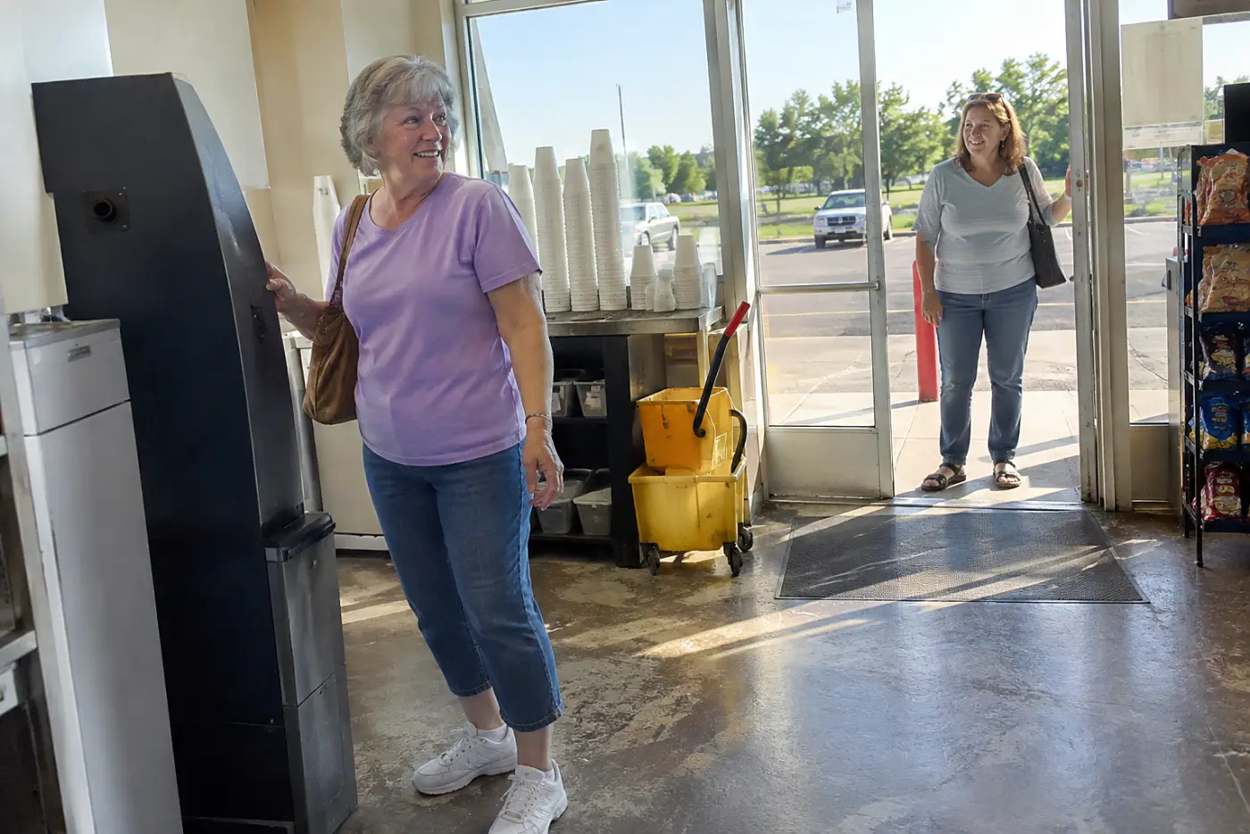 Woman stepping away from a cryptocurrency machine in a convenience store.