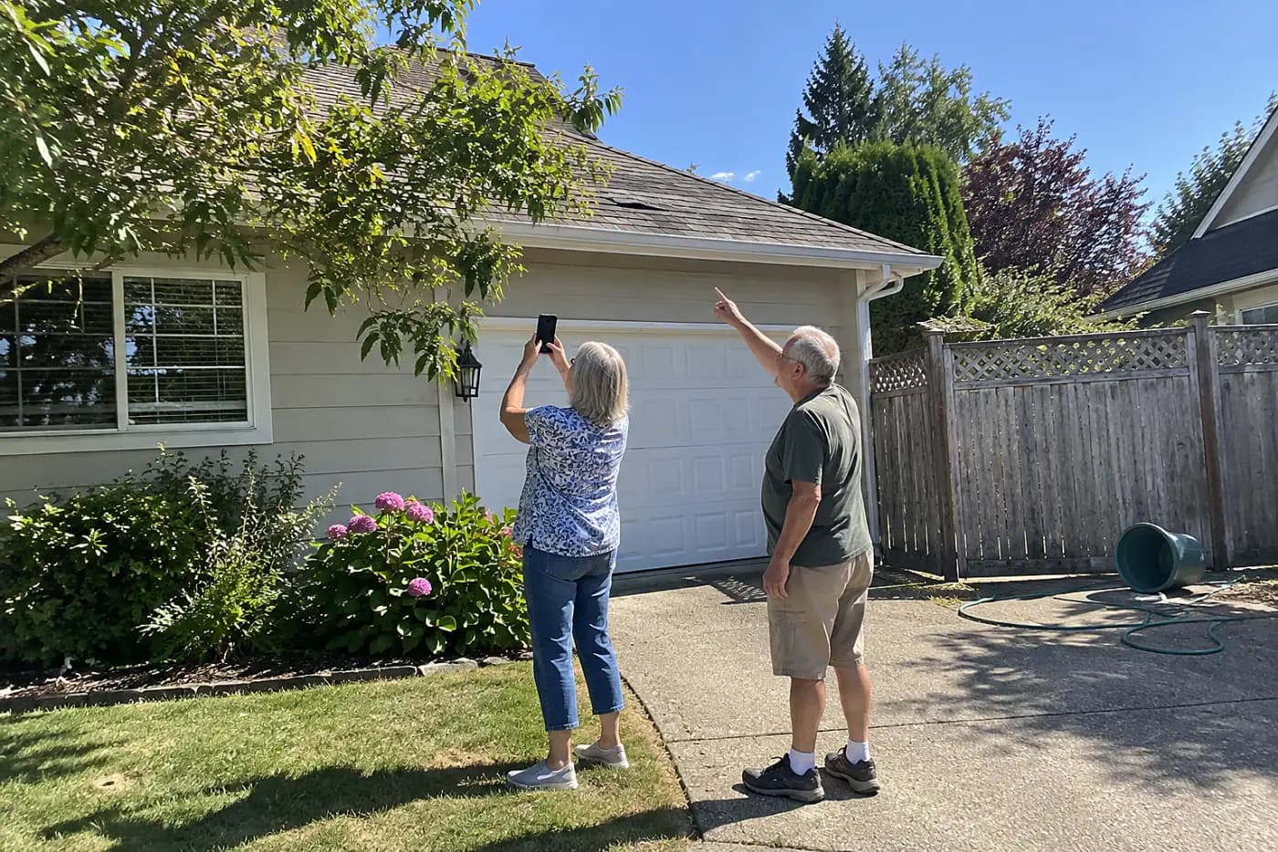 Woman photographing her roof from the sidewalk outside her house.