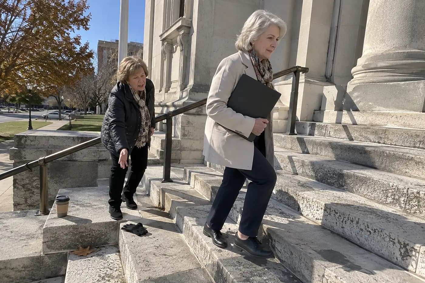 Older woman carrying a document folder into a county courthouse.