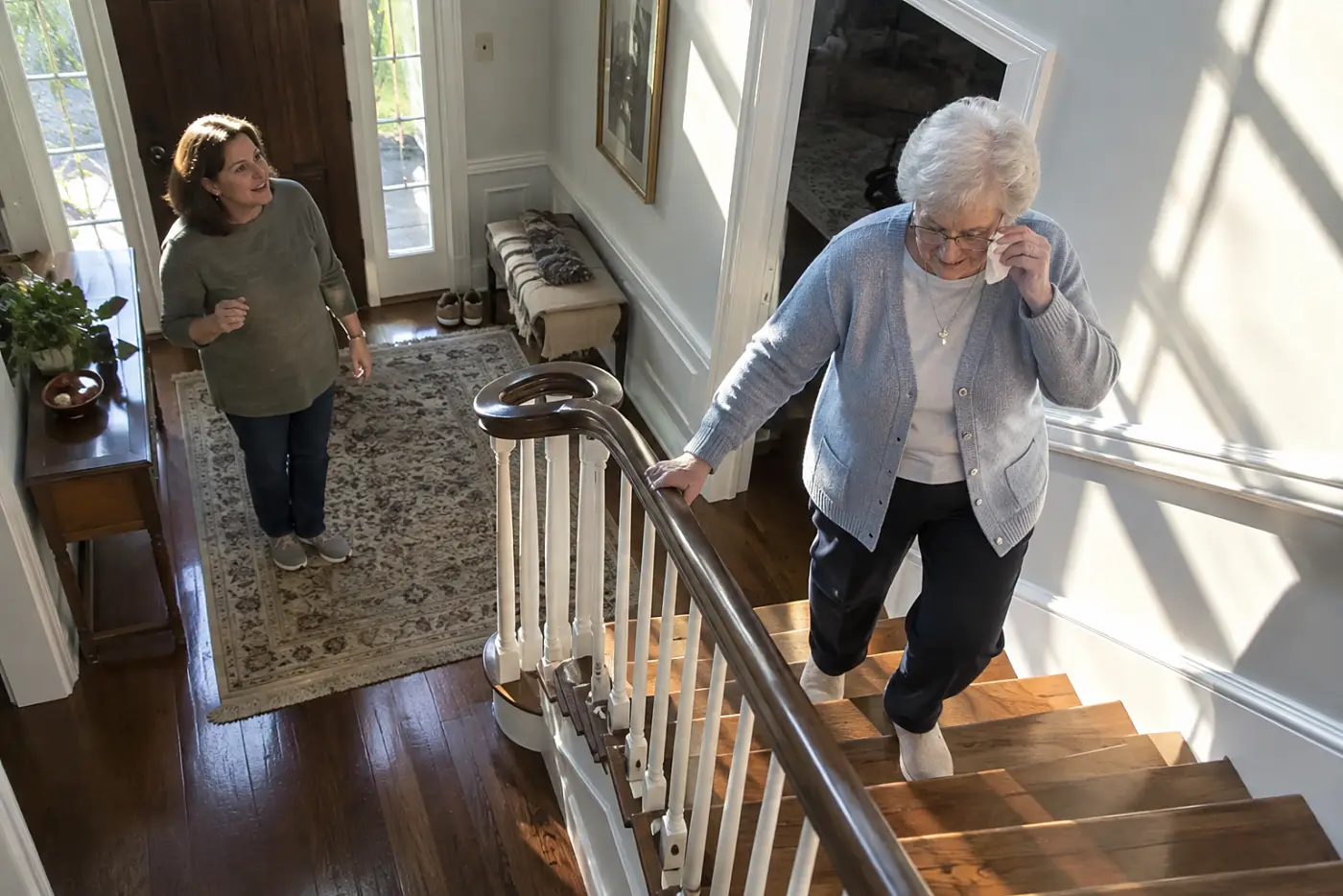 Woman cleaning her glasses before walking down her staircase.
