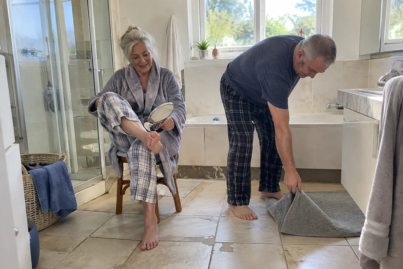 Woman looking at the sole of her foot with a mirror after a shower.