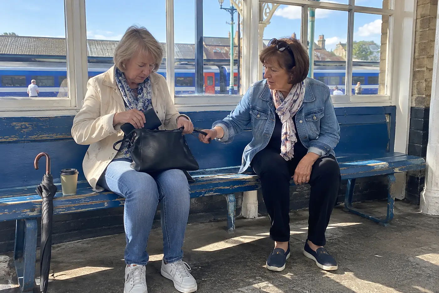 Woman placing her passport in a handbag at a station bench.
