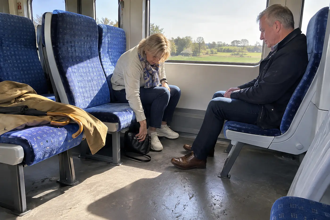 Woman placing a small handbag beneath her train seat.