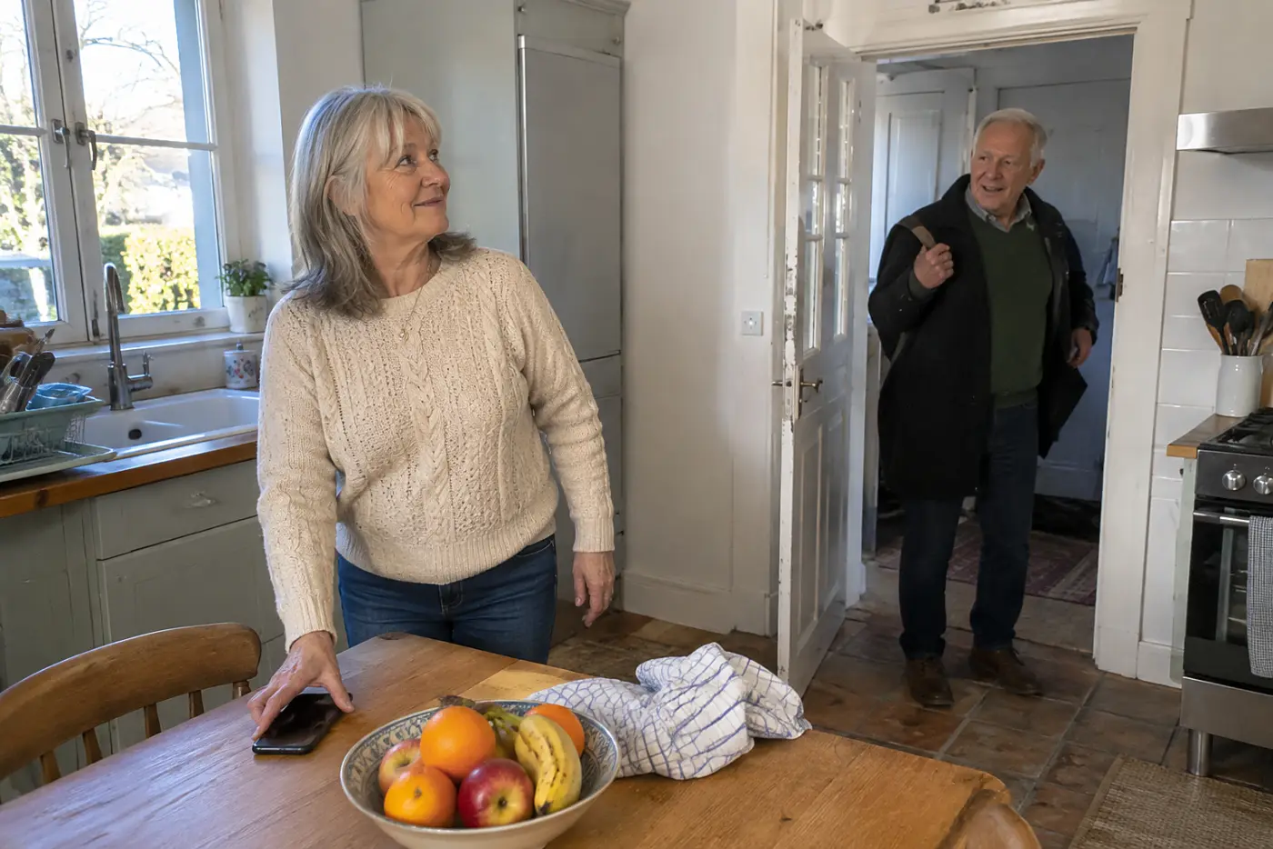 Older woman checking her phone settings at a kitchen table before leaving.
