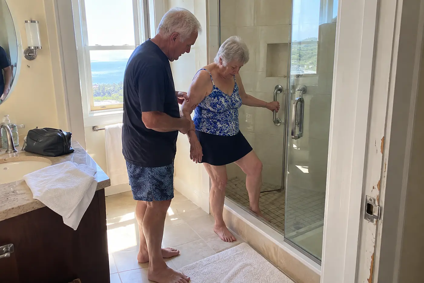 Older woman checking the shower entry in a hotel bathroom.