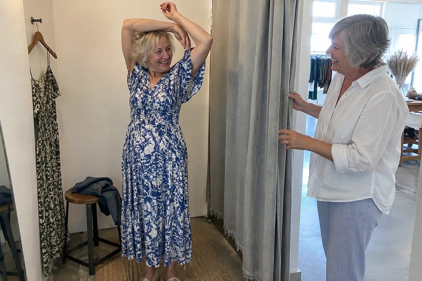 Woman raising her arms in a dress inside a fitting room.