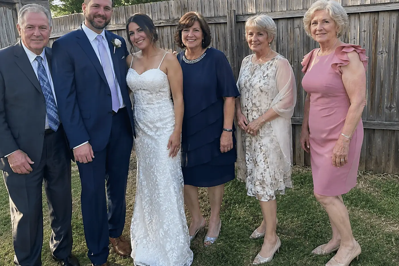 Relatives gather for a wedding photograph as a woman in her sixties waits beside the group to be called.
