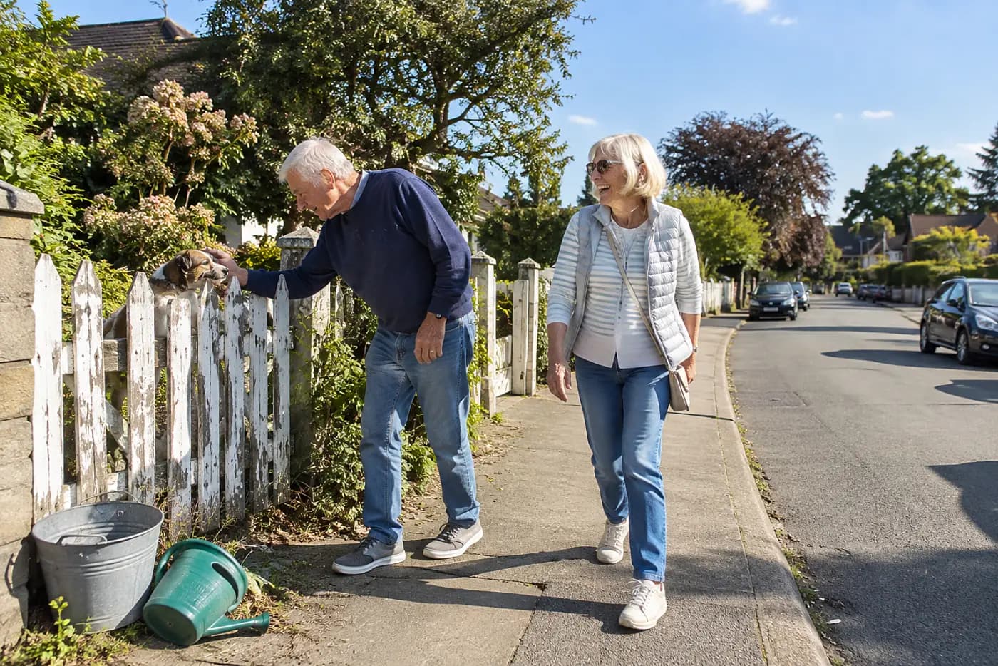 Older woman walking with a friend along her neighborhood sidewalk.