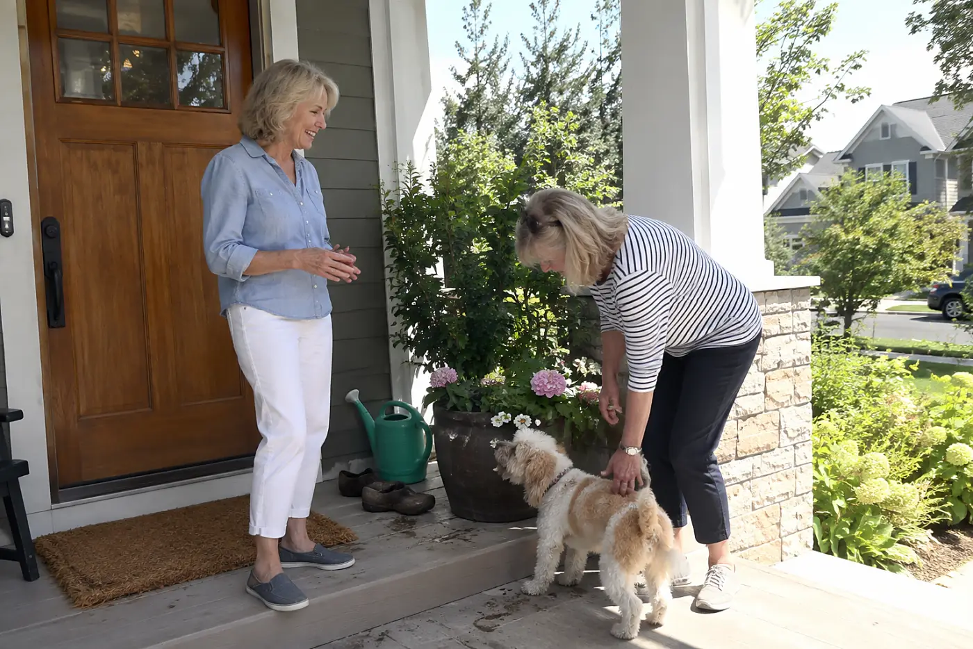 Older woman introducing herself to a neighbor on her front porch.