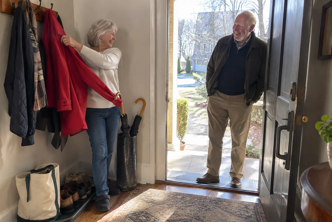 Older woman lifting a red coat from a hook by her front door.