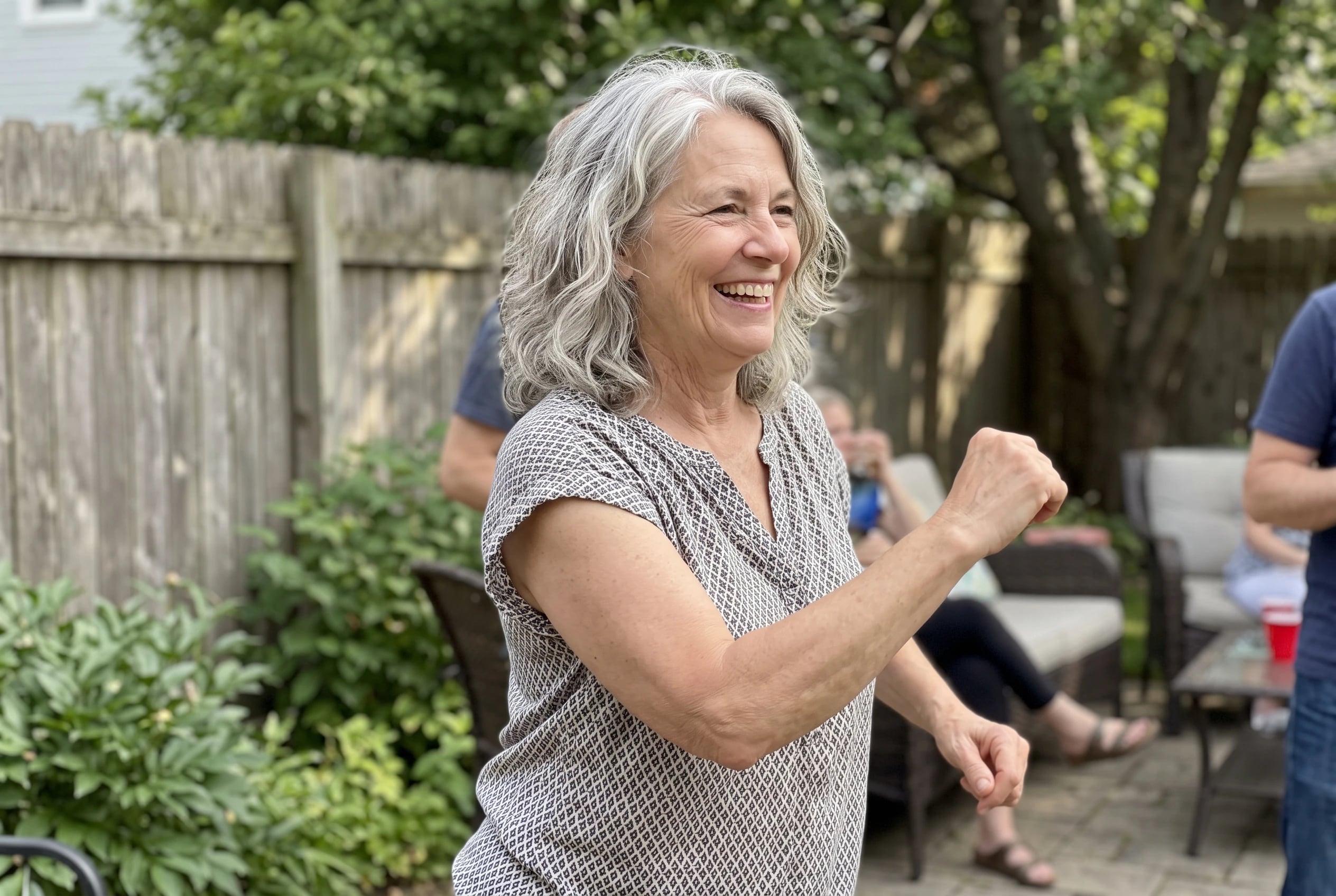 Woman in her sixties swiveling through the Twist at a backyard party.