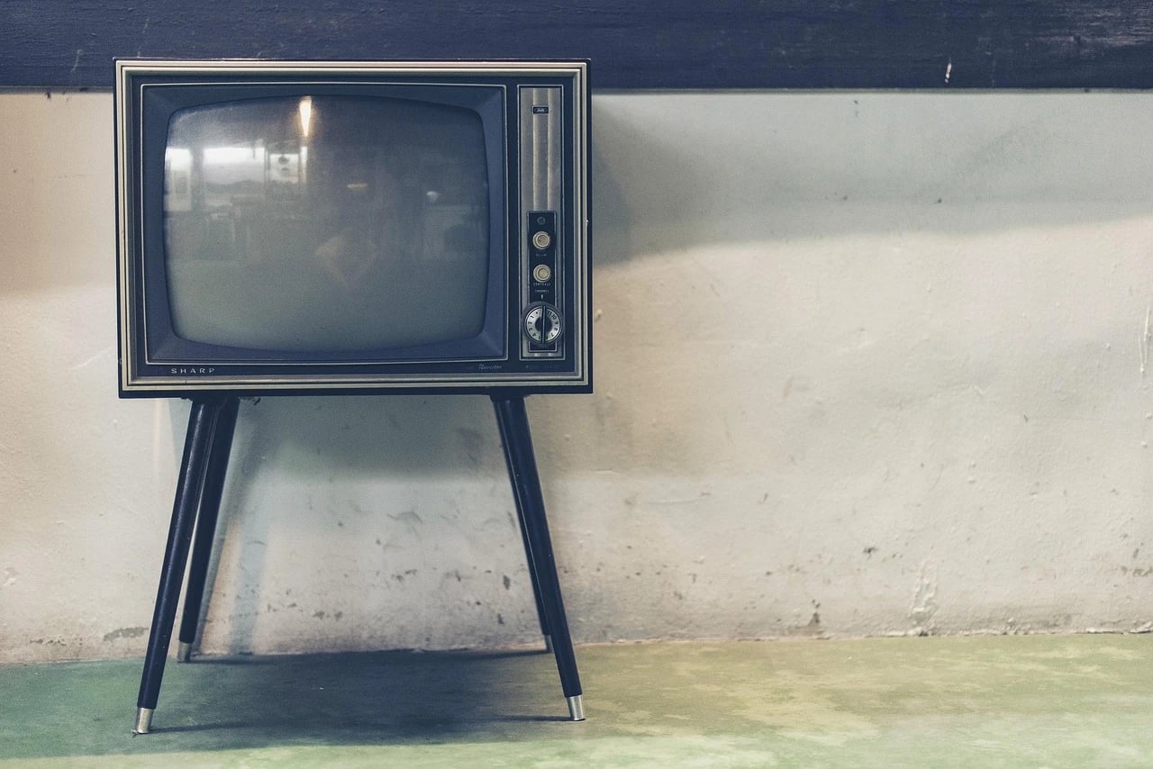 Vintage Sharp television set on slender wooden legs against a weathered plaster wall