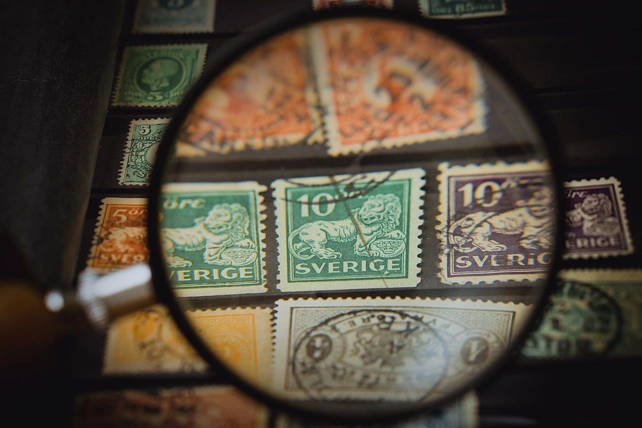 Old Swedish stamps with lion designs seen through a magnifying glass on a stamp album page
