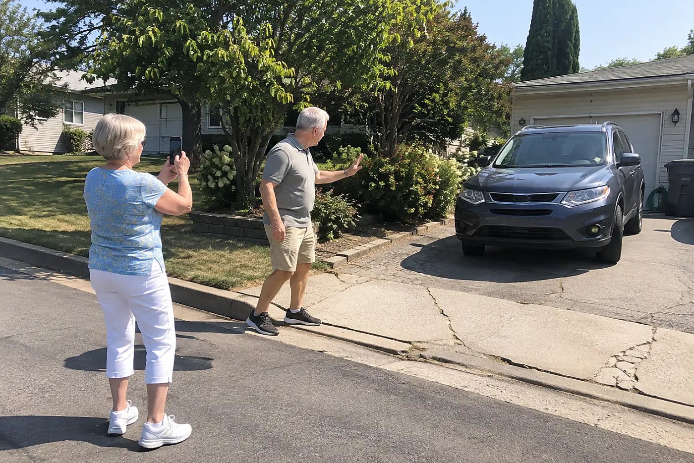 Woman photographing a narrow driveway from the street.