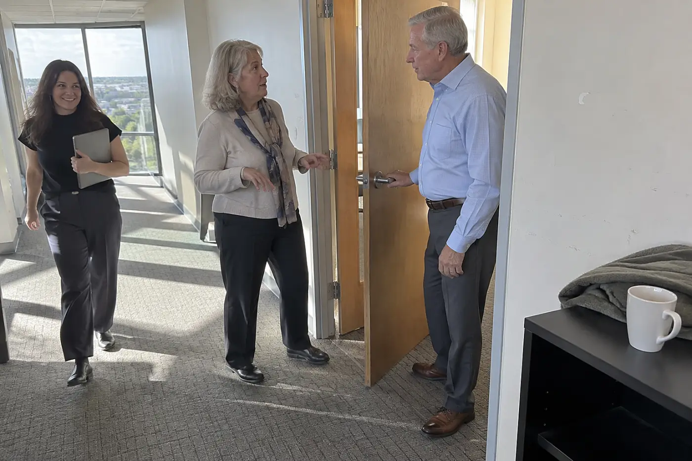 Older woman speaking to her manager in an office hallway.