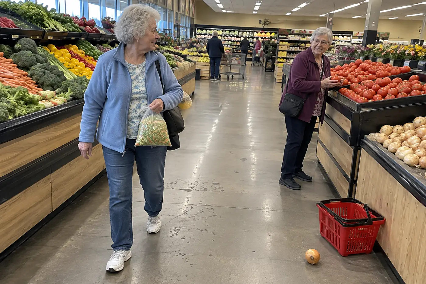 A woman carries frozen vegetables past the produce bins at a grocery store.