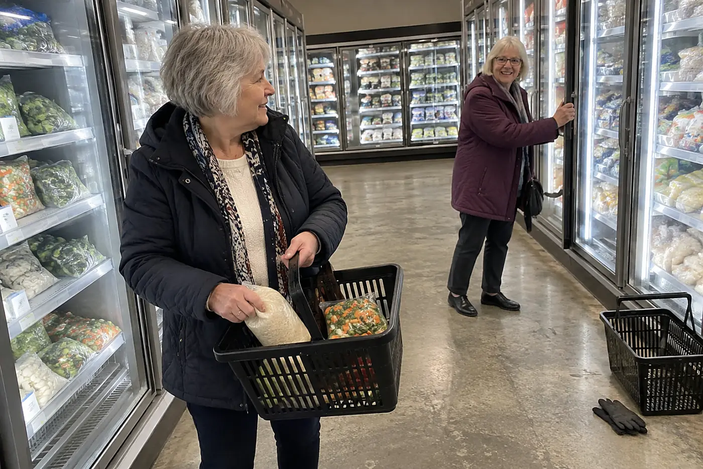 A woman places a rice pouch beside frozen vegetables in a grocery store freezer aisle.